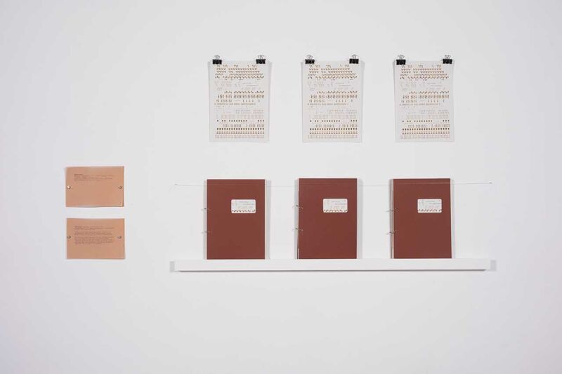 A gallery wall with image, a shelf with three books facing forwards on it, two the left two horizontal pictures. Details are unclear. 