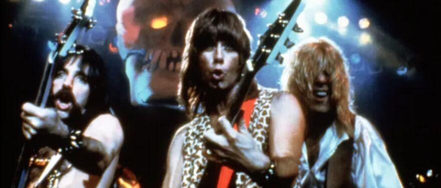 A group of people with mullets wearing leopard print clothes rock out while playing guitars