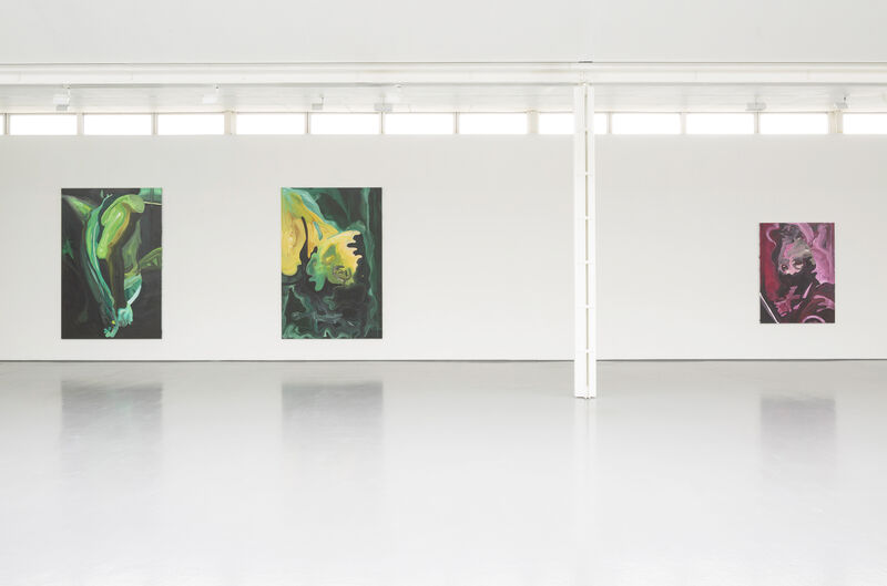Installation view of a gallery with bright natural light and white walls. We can see three paintings from a distance. The paint strokes are bold and broad. 