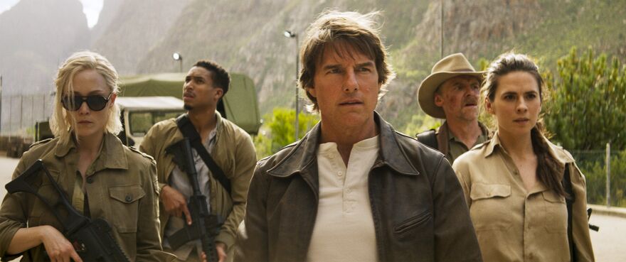 Tom Cruise stands with a group of people all wearing camouflage.