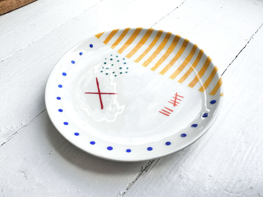 White plate with blue and greeen dots, yellow stripes and red marks