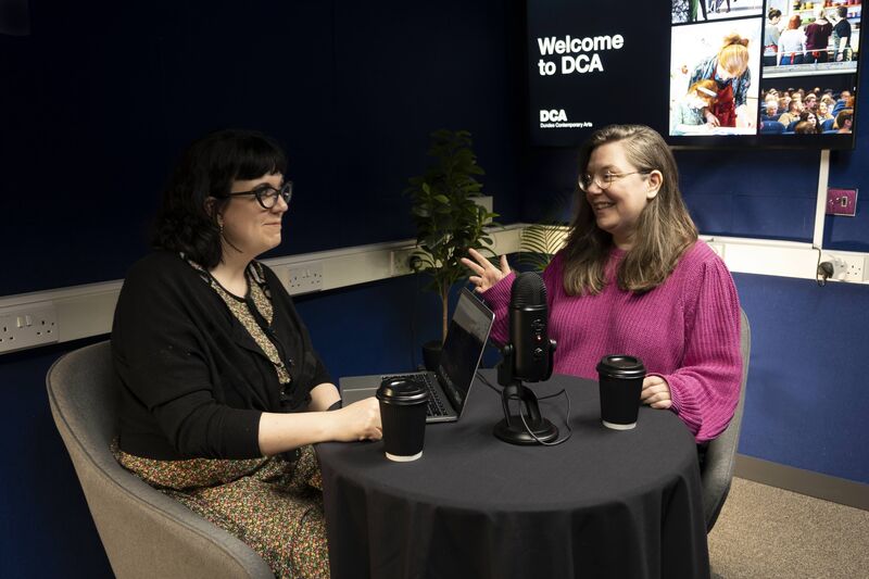 Two people record a podcast using a professional microphone in DCA's Media Suite.