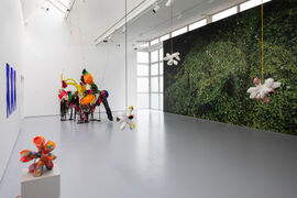 A wall with the image of a plant covering it and colourful hanging sculptures suspected from the ceiling