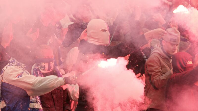 football hooligans in masks and red smoke flares