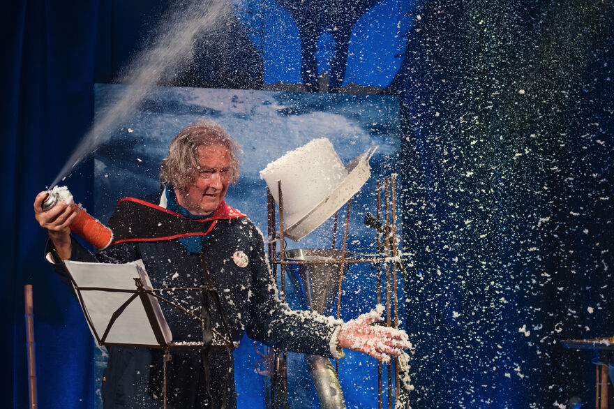Comedian the Ice Man on stage spraying foam in a chaotic scene.