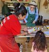 DCA staff member showing adult and child how to marble onto paper