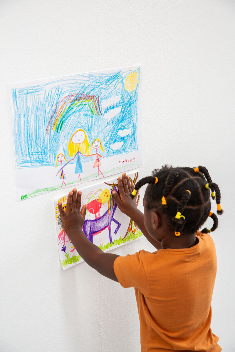 Child adding a drawing of a unicorn to the gallery wall