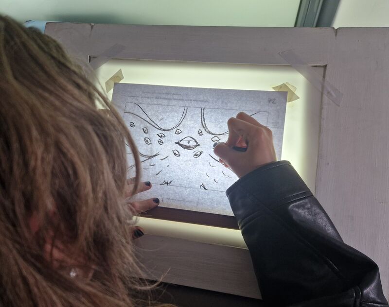 Person drawing a scene for an animation using a lightbox