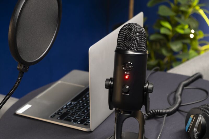 A laptop and professional microphone sit on a table.