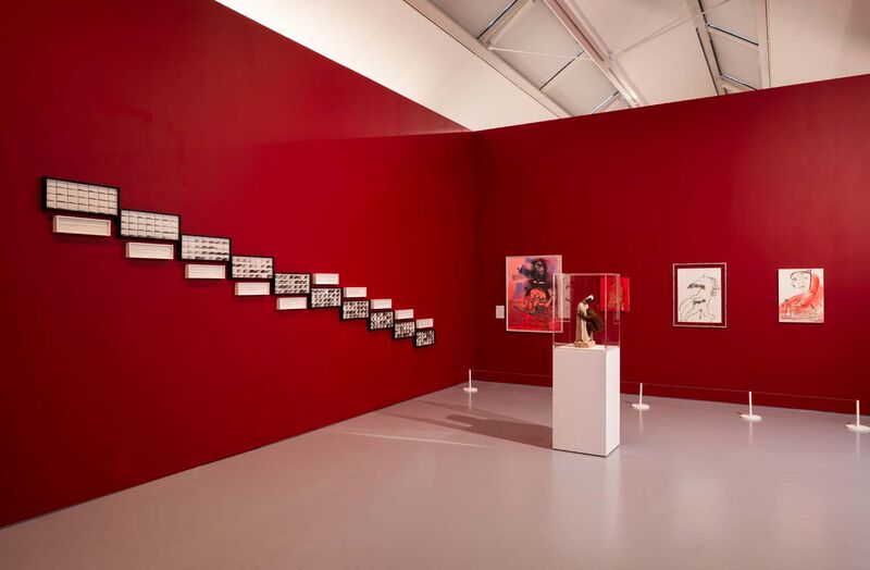 The corner of a red gallery with photos, images and paintings on the wall