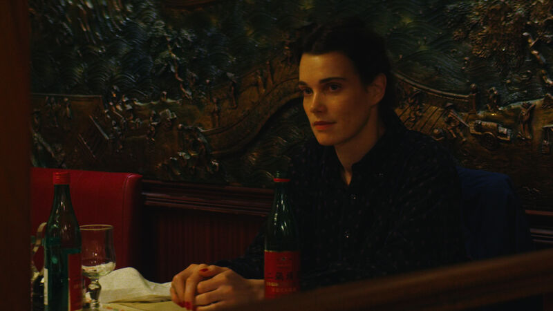 A young woman with a pensive expression sits at a restaurant table