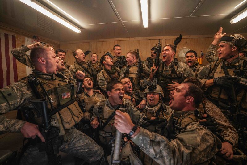A large group of soldiers in camouflage celebrate.