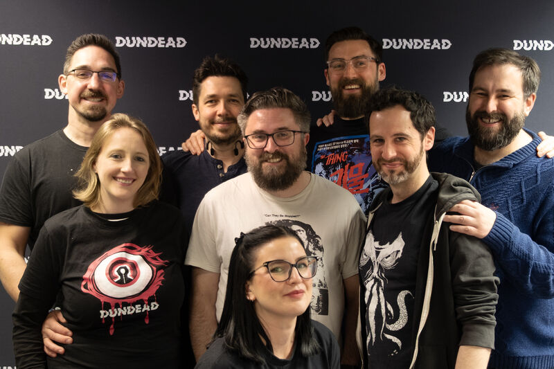 Group of people posing in front of Dundead backdrop