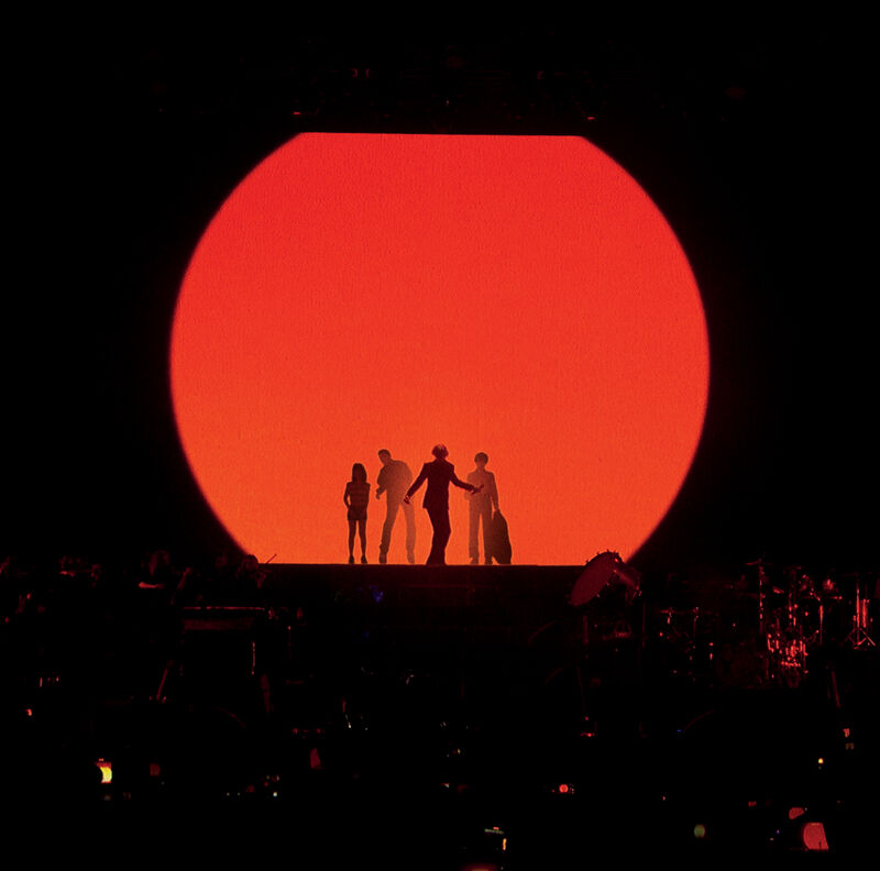 A group poses in front of a large run circle in front of a crowd