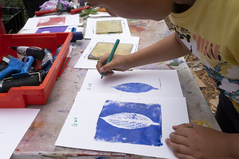 Child adding their name to a leaf print