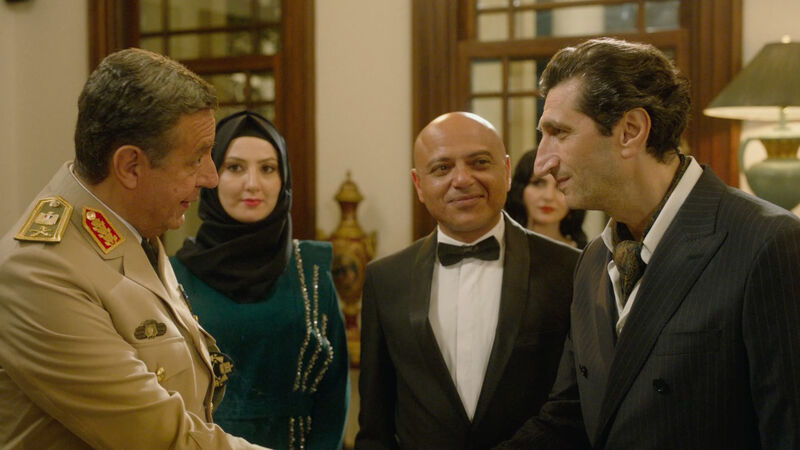 Men in military uniform shakes the hand of a man in a suit 
