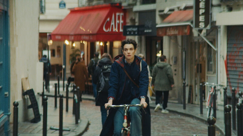 A young woman cycles her bike through the cobbled streets of Paris.