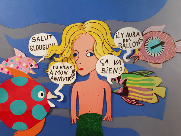 Papercut image of a young mermaid surrounded by fish.