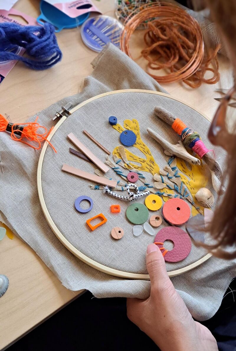 Person stitching objects onto fabric held by an embroidery hoop