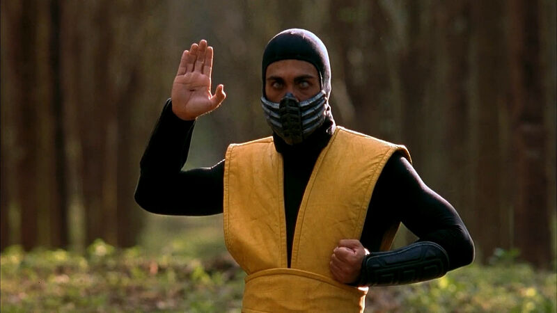 Man wearing a mark and yellow tunic holding his hand in a fighting pose
