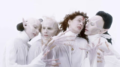 Three vampires with pointy ears surround a woman with a cross on her head