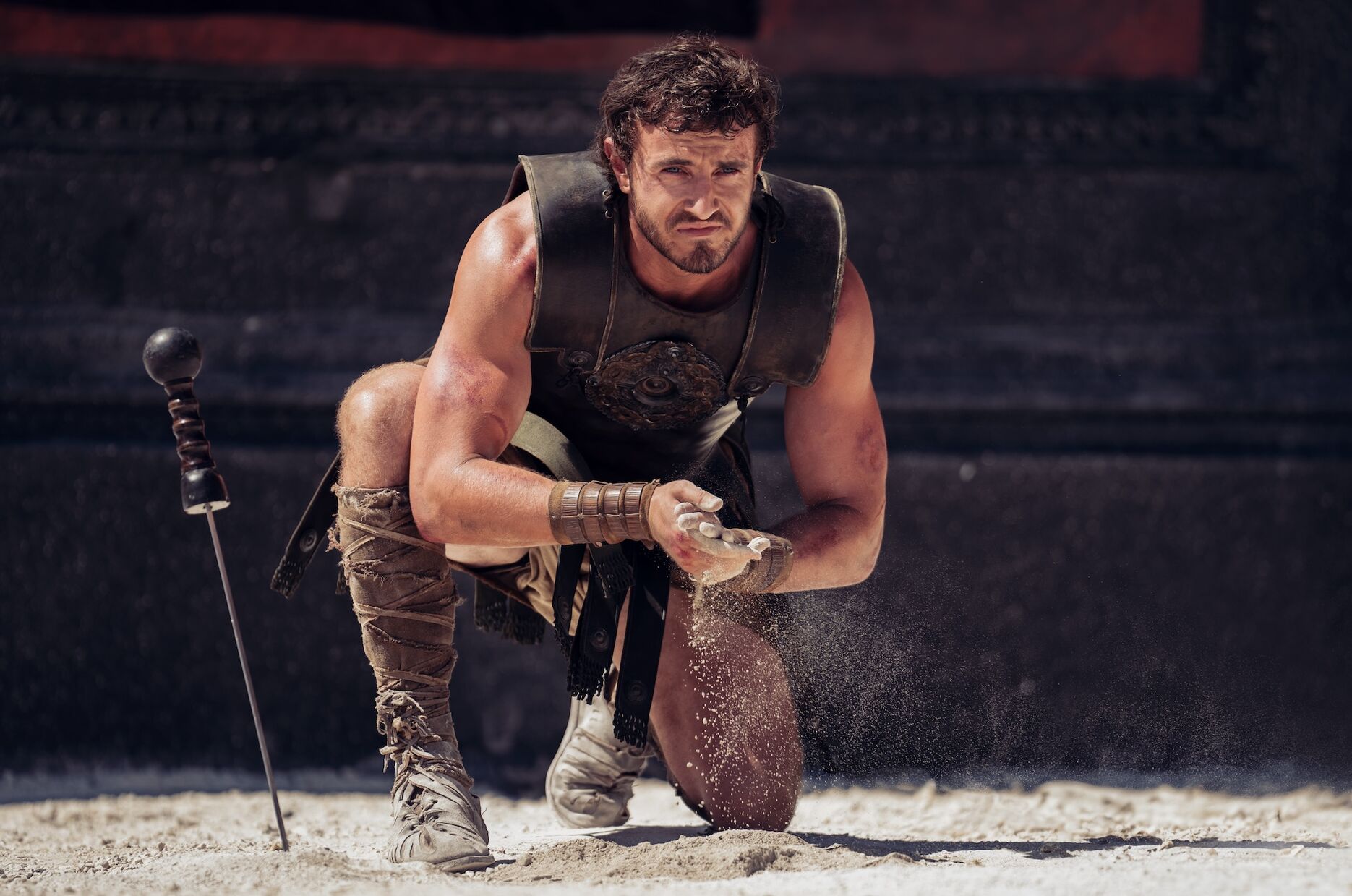 Paul Mescal kneels and dusts his hands, his sword by his side, in Gladiator 2