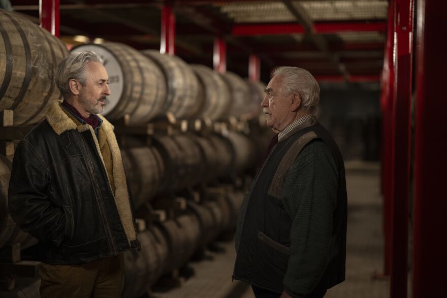 Alan Cumming and Brian Cox surrounded by whisky barrels in a scene from Glenrothan.