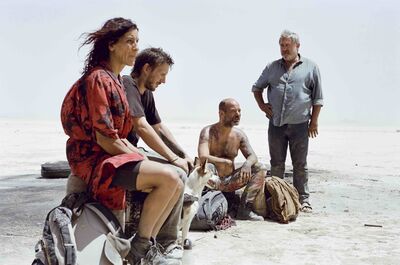 A group of four people sit in the windy desert
