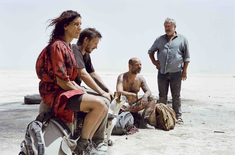 A group of four people sit in the windy desert