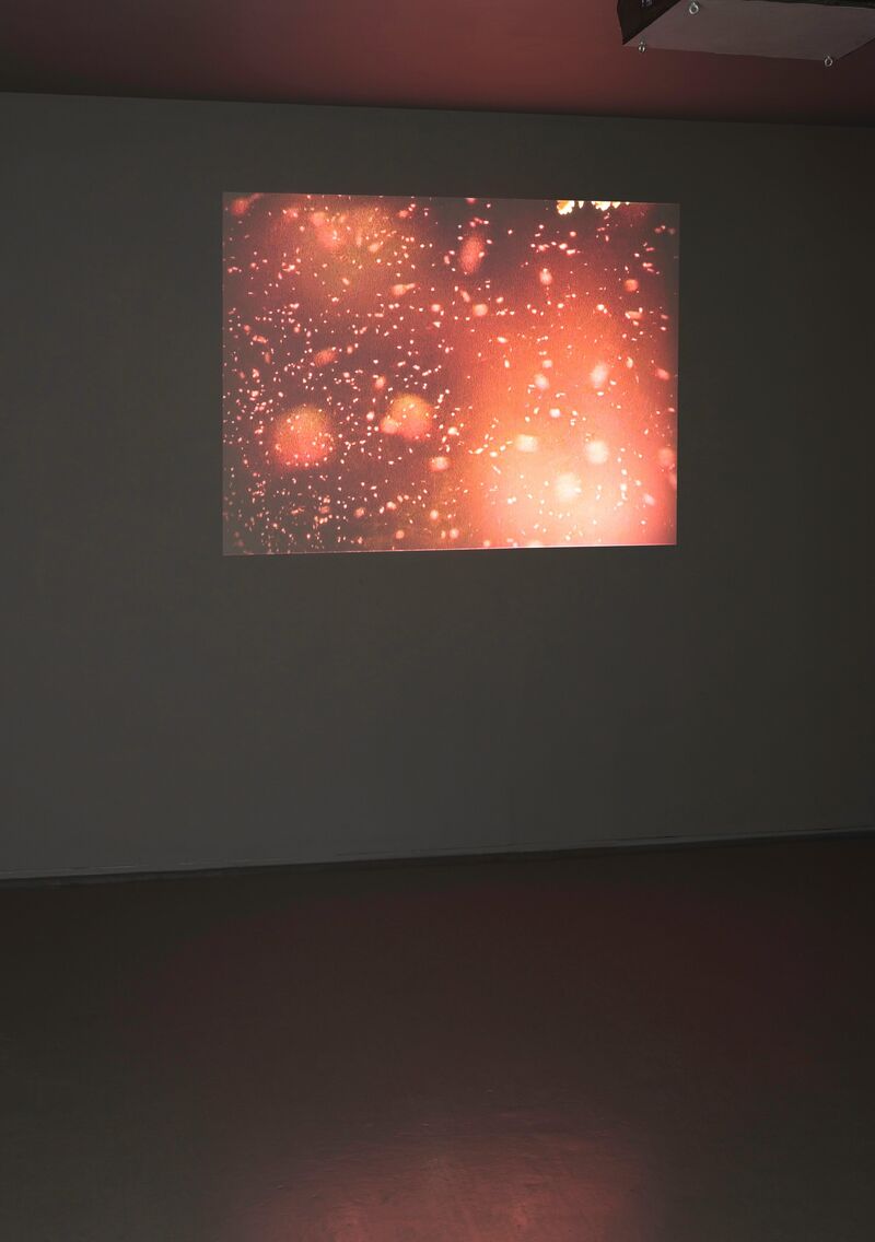 From Duncan Marquiss's exhibition, Copying Errors. A projection screen shows pink, red and orange light splotches against a dark background.