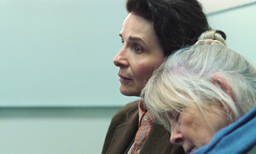A sad woman sits in a waiting room while an older woman leans her head on her shoulder