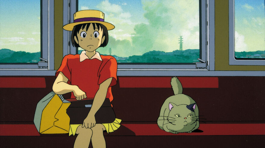 A young girl sits on a train next to a grumpy cat