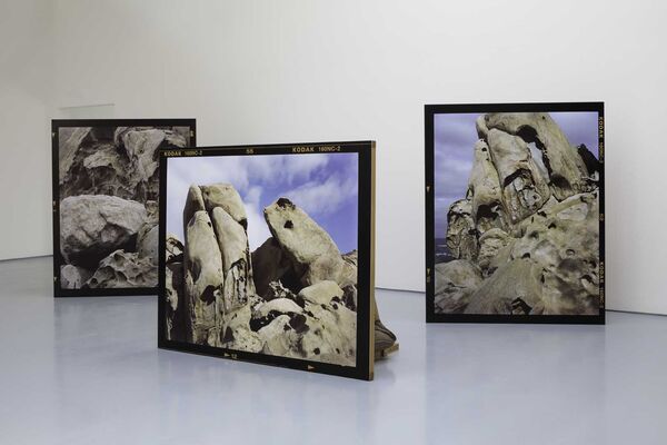 Three large freestanding photographs of rock formations displayed in the gallery.