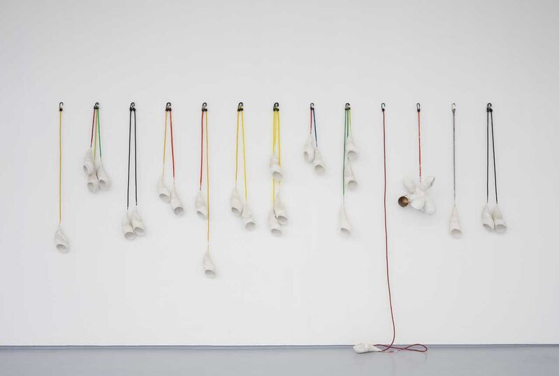 Scupltures of arm casts hanging on a wall using colourful rope