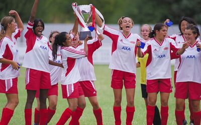 A girls football team celebrating with a trophy
