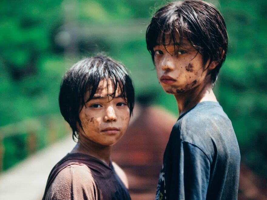 Two boys with mud on their face look at the camera.
