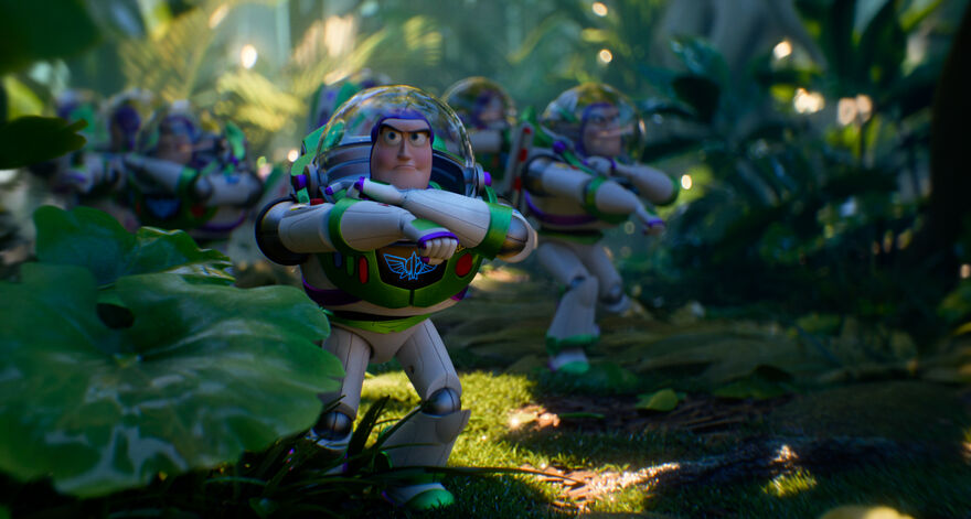 Several Buzz Lightyear toys march through a leafy, jungle-like garden setting, with the front Buzz in focus wearing a clear space helmet and crossing his arms as sunlight filters through the plants.