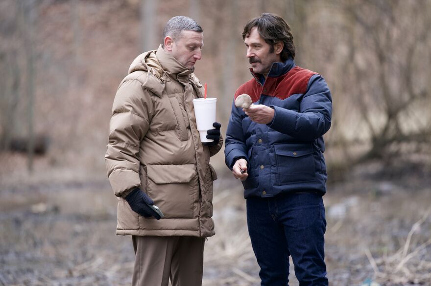 Two men wearing winter coats stand outside looking at a bone.