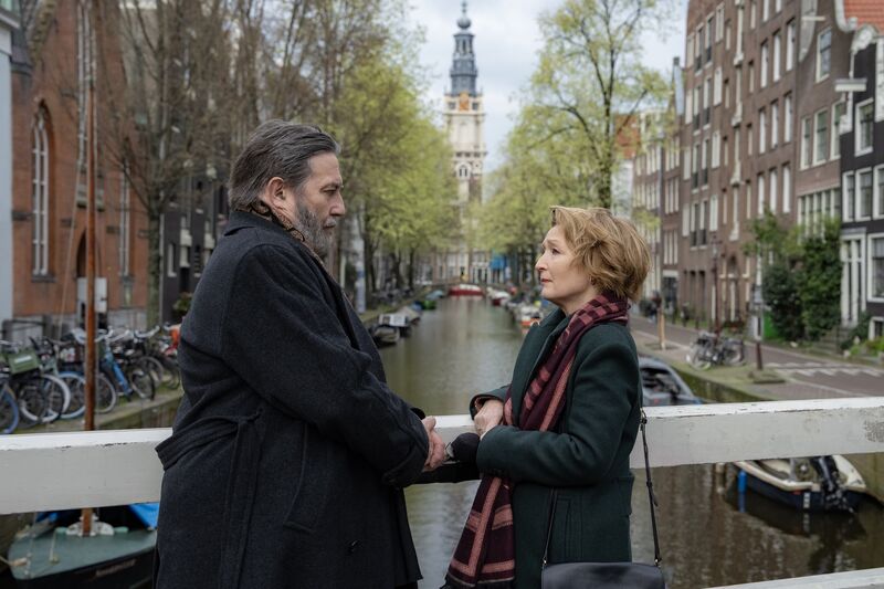 A man and woman standing facing each other on a bridge in Amsterdam