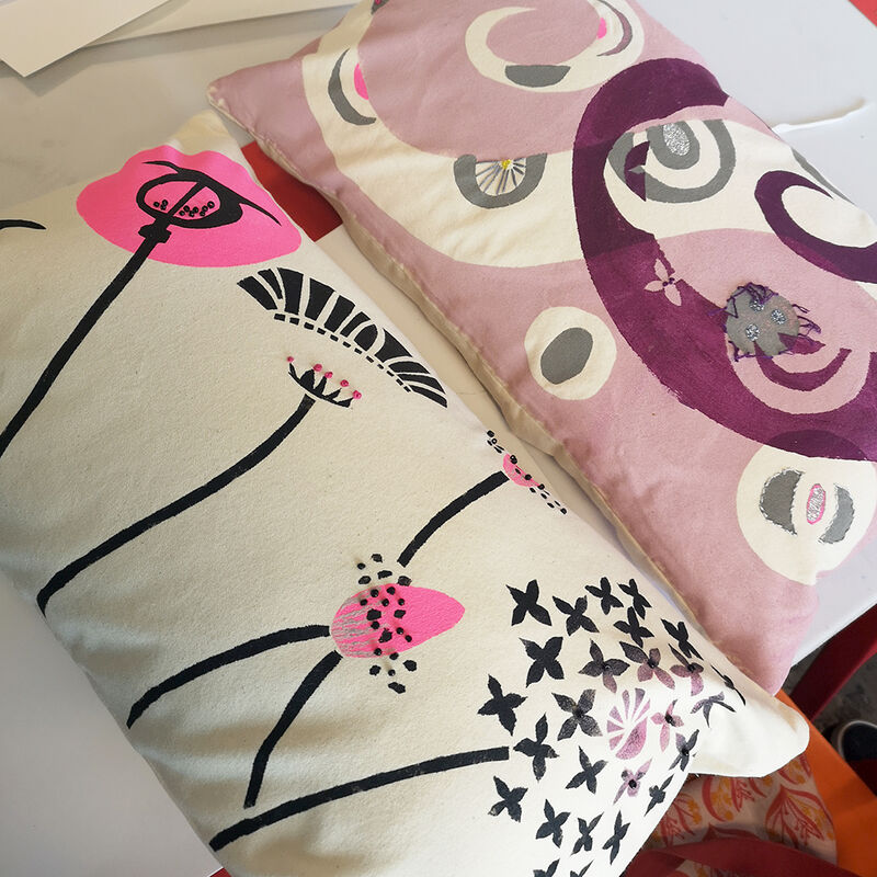 Two log cushions with printed designs with embroidered details