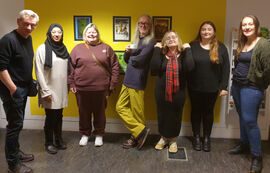 ST/ART participants, volunteers and coordinators standing in front of their display of prints in DCA Create Space