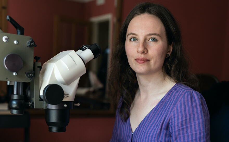 Photo of Anna Ólafsson beside a microscope