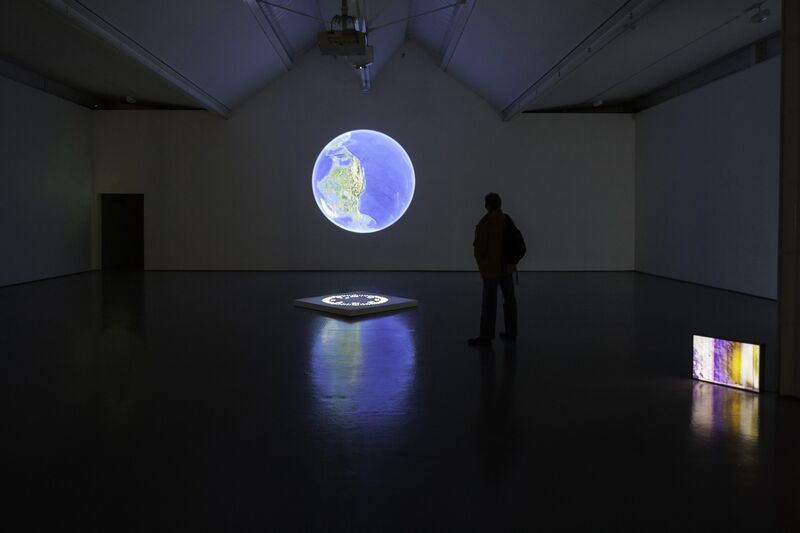 From Thomas & Craighead's exhibition in DCA Galleries. A large image of the globe is projected on the wall. A small tv screen shows brightly coloured patterns.