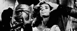 Black and white image of hands holding a woman's face while someone puts a mask on her