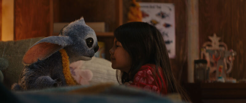 A little girl looks at a blue, fluffy alien