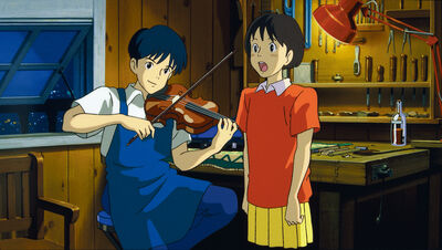 A boy plays violin while a girl sings in a workshop
