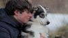 A young man hugs a husky puppy