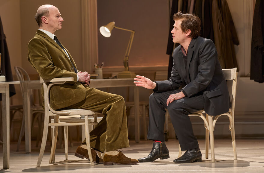 Two men sit across from each other, earnestly discussing