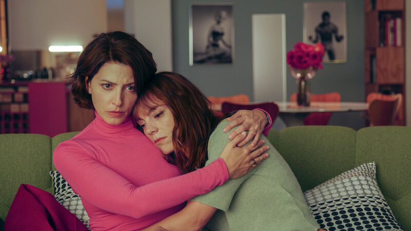 Two sad women hug on a sofa