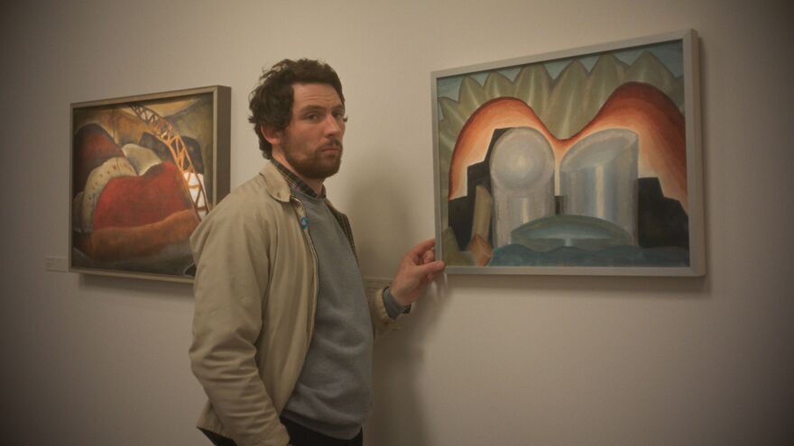 A man stands next to an abstract tpainting